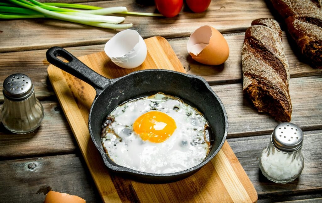 Fried egg in a pan with bread, tomatoes and green onions.
