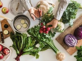 Female hands cutting ingredients for cooking over table with vegetables