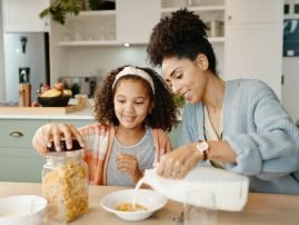 Mother, child and breakfast cereal in morning for healthy nutrition with calcium milk, preparing or